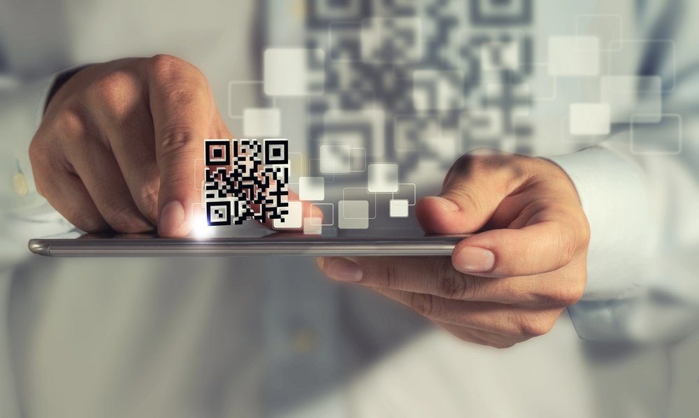 Dłonie trzymające tablet ze skanowanym kodem QR
